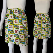 Load image into Gallery viewer, A high-waisted, pleated mini skirt shown from the front and back on white mannequins. The skirts feature a colorful patchwork print of vintage comic book panels with text like 'PLEASE BE SEATED' and 'THAT'S ALL FOLKS!'.