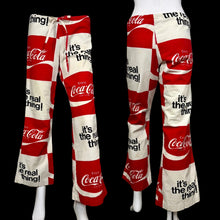 Load image into Gallery viewer, Red and white Coca-Cola themed pants displayed on mannequins against a neutral background.