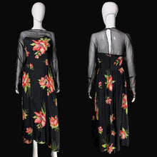 Load image into Gallery viewer, A black maxi dress with a vibrant pink and red floral print and sheer black mesh sleeves, shown from both the front and back on a white mannequin against a black background.