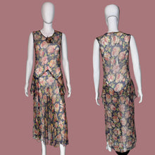 Load image into Gallery viewer, A sleeveless dress with a floral print, shown from both the front and back on a white mannequin. The dress features a navy blue base with pink, red, and green floral patterns, and a ruffled asymmetrical hem.