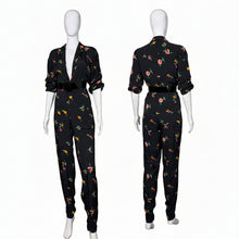 Load image into Gallery viewer, Black jumpsuit with colorful floral pattern on mannequins against a white wall.