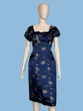 Load image into Gallery viewer, Navy blue dress with white floral pattern on a mannequin against a beige wall.