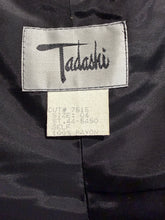 Load image into Gallery viewer, Close-up of a Tadashi label on a dark fabric background