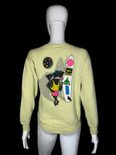 Load image into Gallery viewer, Light yellow sweatshirt with colorful graphic design on a mannequin against a gray background