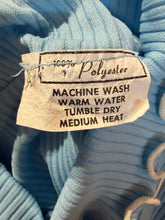 Load image into Gallery viewer, Fabric tag on a blue textured fabric with washing instructions.