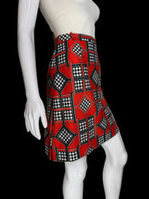 Load image into Gallery viewer, Mannequin wearing a white top and red patterned skort on a plain background.