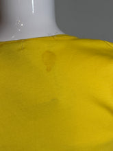 Load image into Gallery viewer, Close-up of a yellow fabric with a dark stain on a plain background