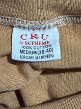 Load image into Gallery viewer, Clothing label on a beige fabric background