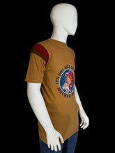 Load image into Gallery viewer, Mannequin wearing a brown t-shirt with a graphic design on the back against a plain background