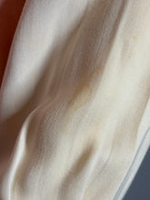 Load image into Gallery viewer, Close-up of beige fabric with a visible stain on a gray background