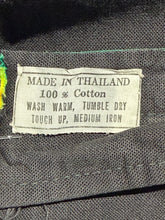 Load image into Gallery viewer, Fabric label on a piece of clothing with text about material, care instructions, and origin.