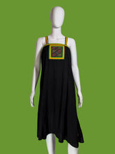 Load image into Gallery viewer, Black dress with colorful embroidery on a mannequin against a white wall.