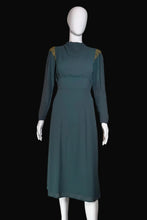 Load image into Gallery viewer, Mannequin wearing a teal dress with gold accents against a white wall.