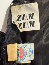 Load image into Gallery viewer, Close-up of a black garment with visible brand labels on a white background