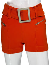 Load image into Gallery viewer, Orange shorts with a belt and zippers on a mannequin against a white background