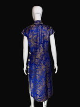 Load image into Gallery viewer, Blue and gold patterned dress on a mannequin against a plain wall.