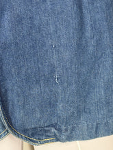 Load image into Gallery viewer, Close-up of a blue denim fabric with a small tear.