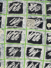 Load image into Gallery viewer, Patterned fabric with black and white designs on a green grid background featuring PCH tag