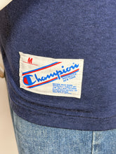 Load image into Gallery viewer, Close-up of a Champion label on blue denim fabric.