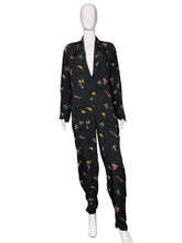 Load image into Gallery viewer, Black jumpsuit with colorful floral pattern against a white wall.
