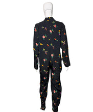 Load image into Gallery viewer, Black jumpsuit with colorful floral pattern on mannequins against a white wall.