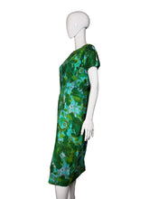 Load image into Gallery viewer, Side view of green patterned dress on a white mannequin against a plain wall.