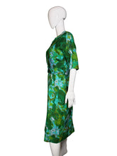 Load image into Gallery viewer, Green patterned dress on a white mannequin against a plain wall.