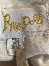 Load image into Gallery viewer, Close-up of a label with 'Rae Dolly' branding on a textured surface