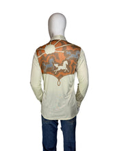 Load image into Gallery viewer, A cream-colored long-sleeve shirt with a large orange, brown, and gray western-style graphic print on the back, displayed on a white mannequin wearing blue jeans against a plain white wall.