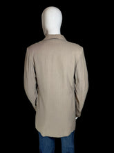 Load image into Gallery viewer, A beige long-sleeve jacket displayed on a white mannequin torso, with blue jeans partially visible underneath