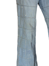 Load image into Gallery viewer, Close-up of a light blue denim garment, showing the fabric texture, grid quilting pattern, and small white bleach splatters on the surface.