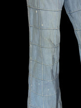 Load image into Gallery viewer, Close-up of a light blue denim garment, showing the fabric texture, grid quilting pattern, and small white bleach splatters on the surface.