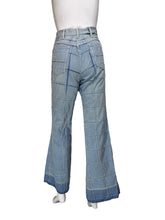 Load image into Gallery viewer, Light blue denim jeans with a grid-like patchwork pattern, displayed on a white mannequin torso against a plain white wall.
