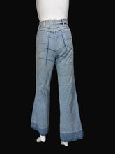 Load image into Gallery viewer, Light blue denim jeans with a grid-like patchwork pattern, displayed on a white mannequin torso against a plain white wall.