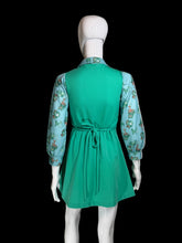 Load image into Gallery viewer, A green dress displayed on a white mannequin, featuring a solid green gathered skirt and light blue floral long sleeves.