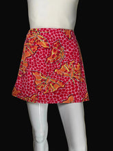 Load image into Gallery viewer, A red and orange patterned mini skirt with butterfly and polka dot motifs, displayed on a white mannequin.