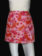 Load image into Gallery viewer, A pink fabric skirt featuring a pattern of orange and red tigers, yellow and red flowers, and black stripes, displayed on a white mannequin.