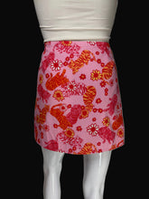 Load image into Gallery viewer, A pink mini skirt with a pattern of orange and red tigers and flowers, displayed on a white mannequin.