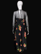 Load image into Gallery viewer, A black long-sleeve maxi dress with a pink and green floral print, displayed on a white mannequin in front of a black background.
