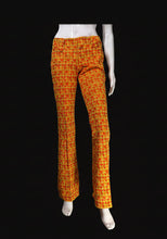 Load image into Gallery viewer, Orange and yellow patterned flared pants displayed on a white mannequin with a black background.