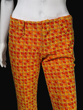 Load image into Gallery viewer, Bright orange and yellow geometric patterned pants displayed on a white mannequin against a black background.