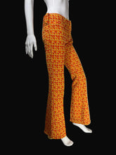 Load image into Gallery viewer, Orange and yellow patterned flared pants displayed on a white mannequin against a black background.