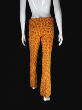 Load image into Gallery viewer, A pair of flared trousers with a textured orange and yellow geometric pattern, displayed on a white mannequin.