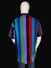 Load image into Gallery viewer, A multicolor striped short-sleeve shirt displayed on a white mannequin against a black background. The shirt features horizontal stripes of blue, purple, green, red, and dark navy.