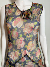 Load image into Gallery viewer, A sleeveless dress with a floral print. The dress features a navy blue base with pink, red, and green floral patterns, and a ruffled asymmetrical hem.