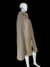 Load image into Gallery viewer, A beige ribbed knit cape with a draped collar and layered hem, displayed on a white mannequin.