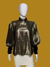 Load image into Gallery viewer, A metallic gold pleated blouse with black long sleeves and a high mock neck, shown on a white mannequin.