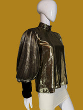 Load image into Gallery viewer, A metallic gold pleated blouse with black long sleeves and a high mock neck, shown on a white mannequin.