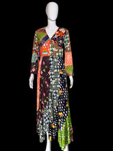 Load image into Gallery viewer, A long-sleeved patchwork maxi dress displayed on a mannequin. The dress features a vibrant multicolor patchwork design with various patterns including houndstooth, polka dots, florals, and plaid in orange, green, pink, black, white, and purple.