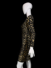 Load image into Gallery viewer, A long-sleeve leopard-print dress displayed on a white mannequin. The dress features a bold black and tan/gold animal print pattern with a button-up front and side pockets.